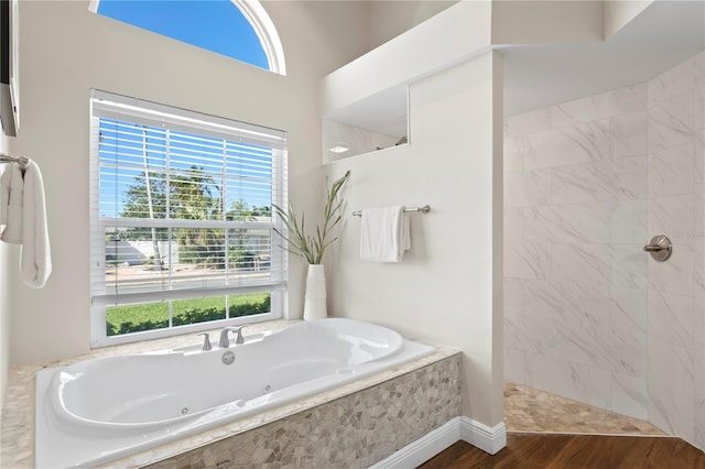 full bath with a jetted tub, wood finished floors, and a tile shower