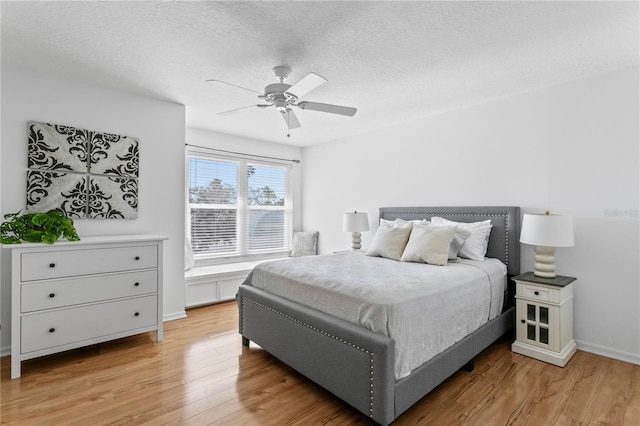 bedroom with baseboards, light wood-style flooring, a textured ceiling, and ceiling fan