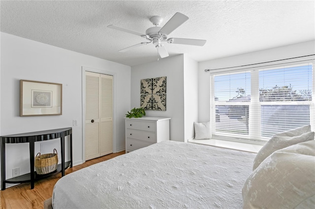 bedroom with a ceiling fan, wood finished floors, a closet, and a textured ceiling