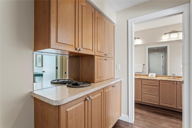 kitchen with light brown cabinets, dark wood finished floors, a peninsula, a sink, and light countertops