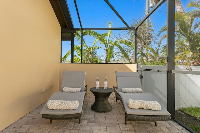 view of patio / terrace featuring a lanai and fence