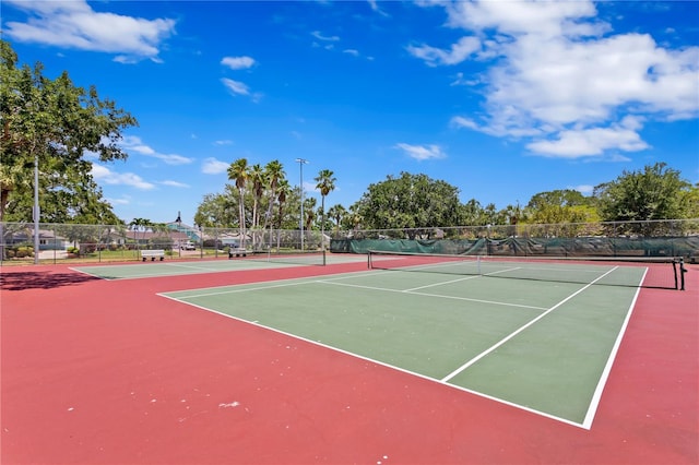 view of tennis court featuring community basketball court and fence