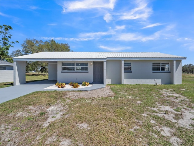 ranch-style home with metal roof, an attached carport, concrete block siding, and driveway