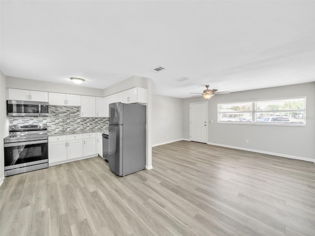 kitchen featuring a ceiling fan, stainless steel appliances, light countertops, open floor plan, and backsplash