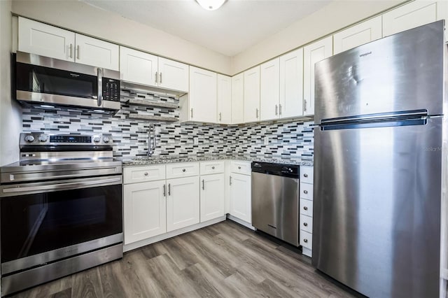 kitchen with white cabinets, backsplash, wood finished floors, and appliances with stainless steel finishes