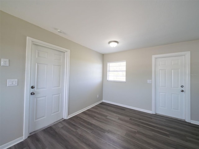 unfurnished room featuring baseboards and dark wood-style flooring