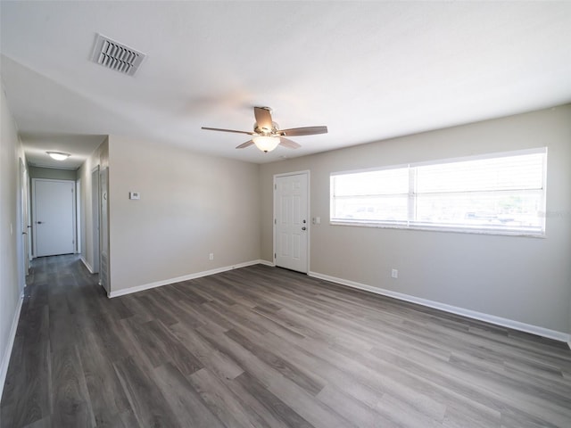 unfurnished room featuring visible vents, ceiling fan, dark wood-type flooring, and baseboards