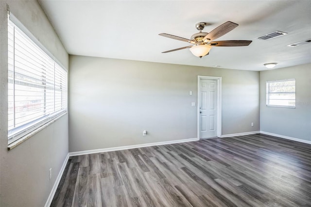 unfurnished room with ceiling fan, wood finished floors, visible vents, and baseboards