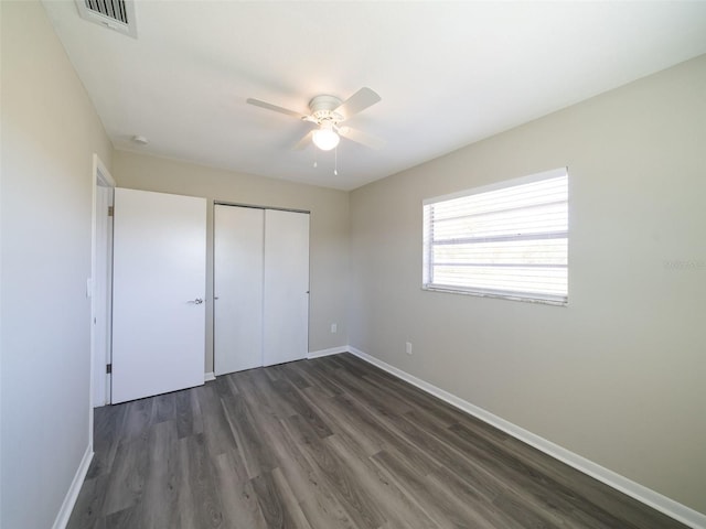 unfurnished bedroom featuring visible vents, dark wood-style floors, a closet, baseboards, and ceiling fan