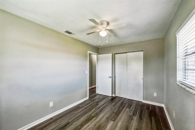 unfurnished bedroom with dark wood-type flooring, baseboards, visible vents, and a closet