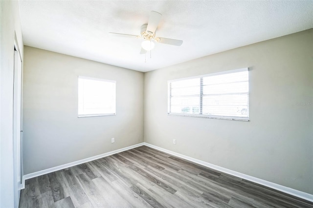 spare room featuring a textured ceiling, wood finished floors, baseboards, and ceiling fan