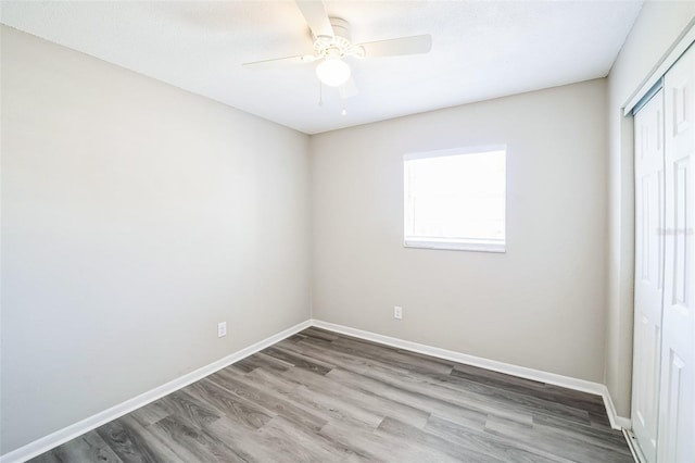 unfurnished bedroom featuring a ceiling fan, wood finished floors, a closet, and baseboards