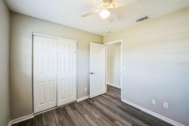 unfurnished bedroom featuring visible vents, baseboards, a closet, a ceiling fan, and dark wood-style flooring