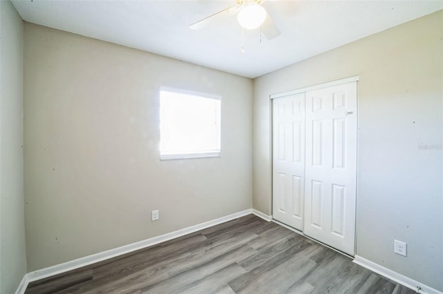 unfurnished bedroom with ceiling fan, a closet, baseboards, and wood finished floors