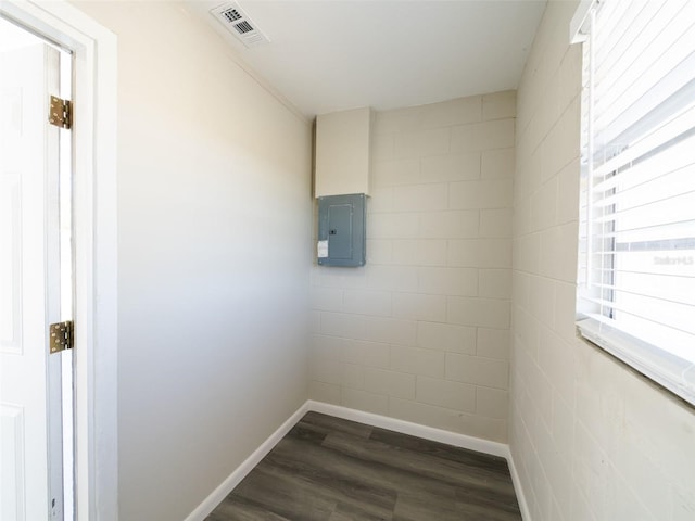 empty room featuring electric panel, visible vents, dark wood-type flooring, and baseboards