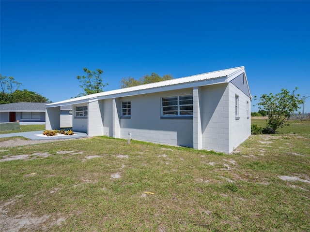 ranch-style home featuring metal roof, a front yard, and concrete block siding