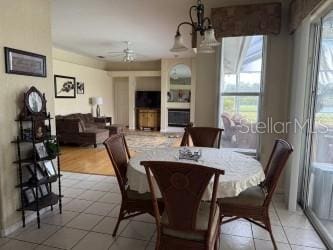 dining area with ceiling fan with notable chandelier and a fireplace