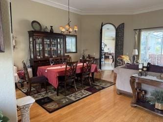 dining area featuring an inviting chandelier, crown molding, and wood finished floors