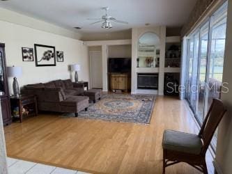 living room with a fireplace, wood finished floors, and ceiling fan