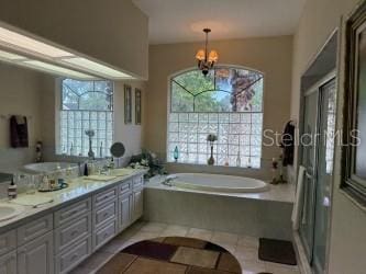 full bathroom featuring a bath, plenty of natural light, tile patterned floors, and an inviting chandelier