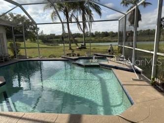 view of pool with a pool with connected hot tub, a lanai, and a patio area