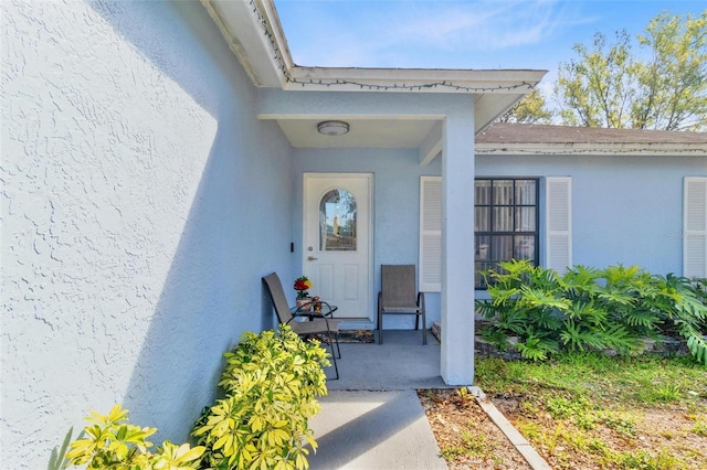 property entrance featuring stucco siding and a shingled roof