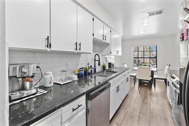 kitchen featuring visible vents, a sink, decorative backsplash, dishwasher, and light wood-type flooring