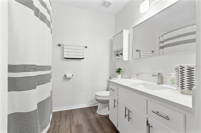 bathroom with visible vents, baseboards, toilet, wood finished floors, and vanity