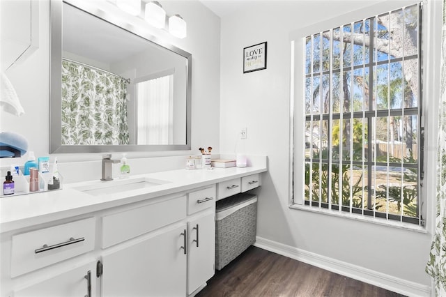 full bath with baseboards, wood finished floors, and vanity