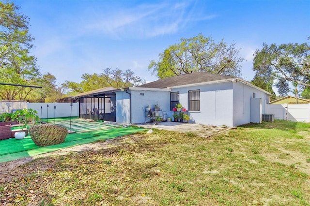 back of property with stucco siding, a lawn, central AC, and a fenced backyard