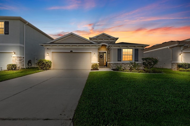 view of front of house with a front yard, driveway, stucco siding, a garage, and stone siding