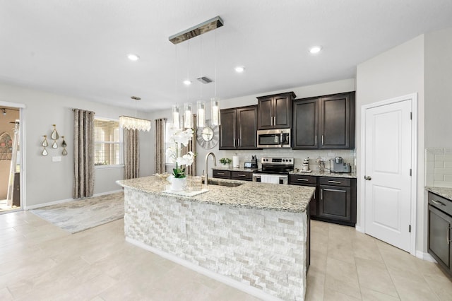 kitchen featuring dark brown cabinets, backsplash, an island with sink, stainless steel appliances, and a sink