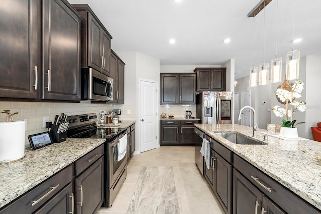 kitchen featuring light stone countertops, a sink, dark brown cabinetry, appliances with stainless steel finishes, and backsplash