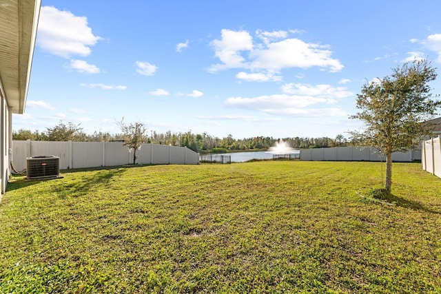 view of yard featuring central AC unit, a fenced backyard, and a water view