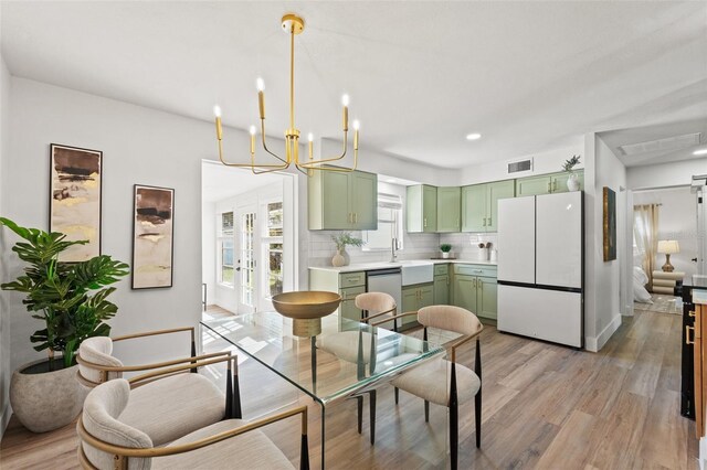 dining area with light wood finished floors, visible vents, recessed lighting, french doors, and a notable chandelier