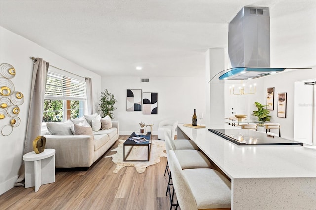 living room with light wood-type flooring, visible vents, and baseboards