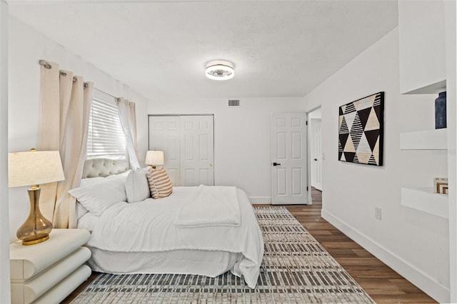 bedroom featuring visible vents, baseboards, a closet, and dark wood-style floors