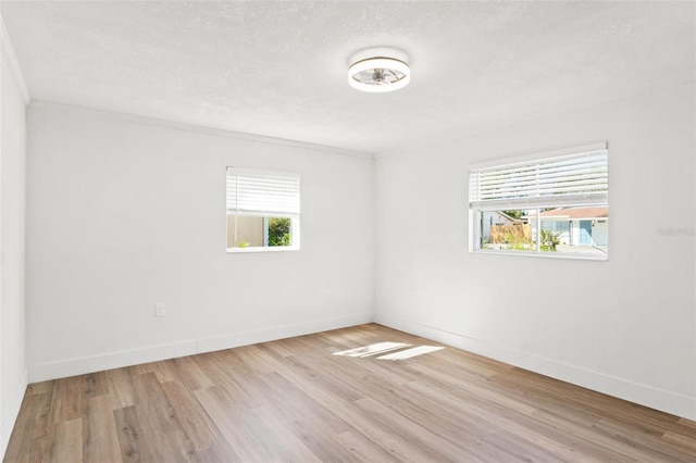 spare room featuring wood finished floors, baseboards, and a wealth of natural light