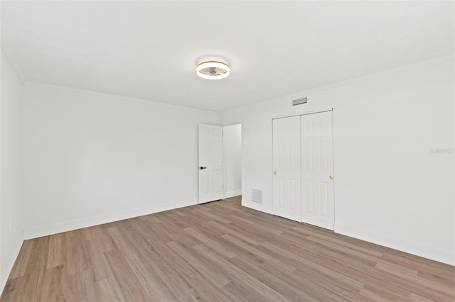 unfurnished bedroom featuring light wood-style floors, visible vents, a closet, and baseboards