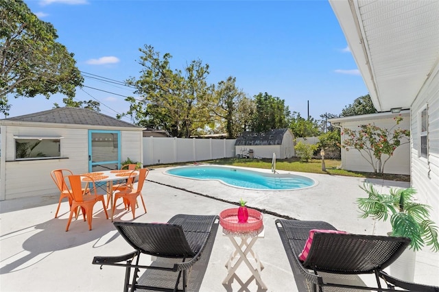 view of swimming pool with a fenced in pool, outdoor dining area, a fenced backyard, an outdoor structure, and a patio area