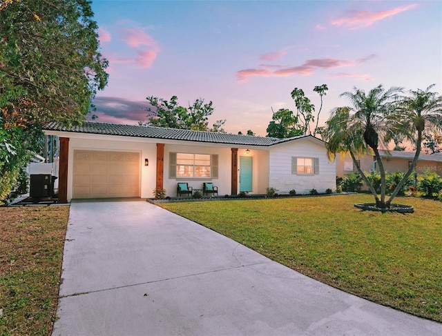 ranch-style house with a front yard, concrete driveway, an attached garage, and a tile roof