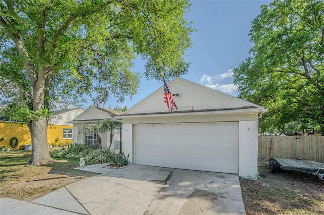 ranch-style home featuring stucco siding, concrete driveway, an attached garage, and fence