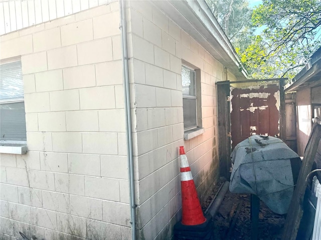 view of property exterior with concrete block siding and fence