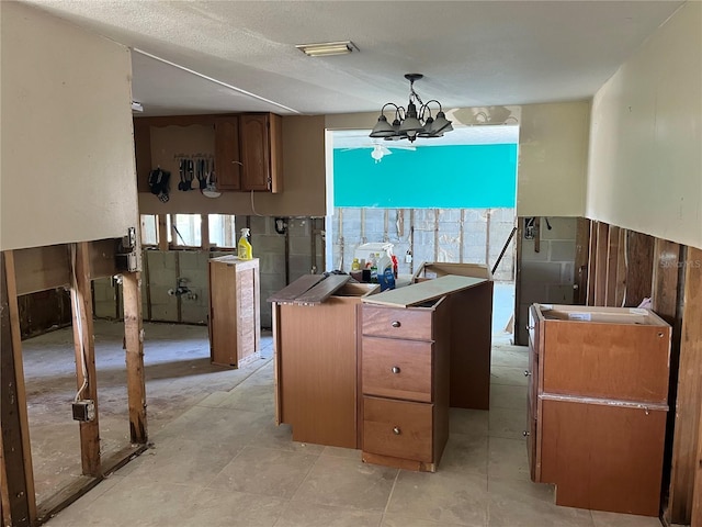 kitchen with hanging light fixtures, an inviting chandelier, visible vents, and brown cabinets