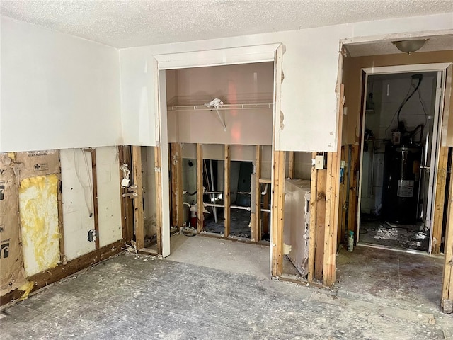 miscellaneous room with water heater and a textured ceiling