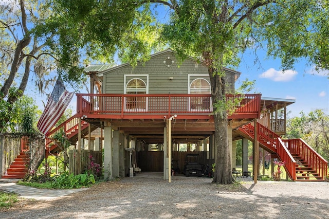 raised beach house featuring driveway, a carport, and stairs