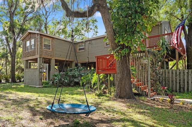 exterior space featuring a wooden deck, a trampoline, stairs, and fence