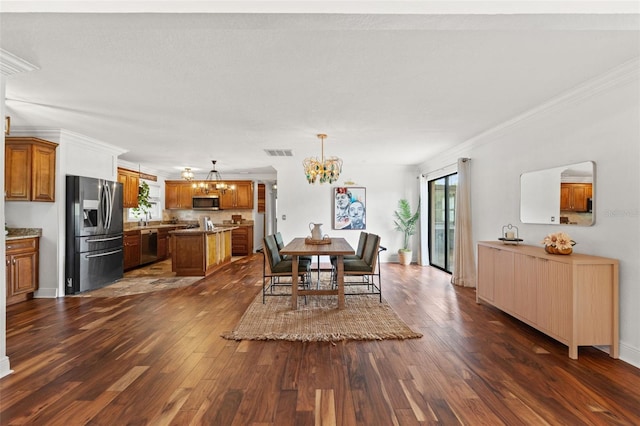 dining space featuring visible vents, dark wood finished floors, crown molding, baseboards, and a chandelier