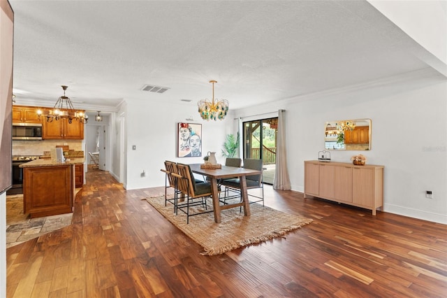 dining area featuring dark wood finished floors, visible vents, a textured ceiling, and an inviting chandelier