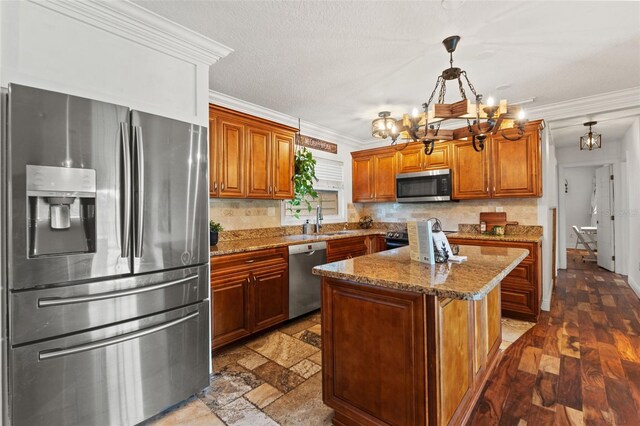 kitchen featuring a sink, a notable chandelier, appliances with stainless steel finishes, and ornamental molding